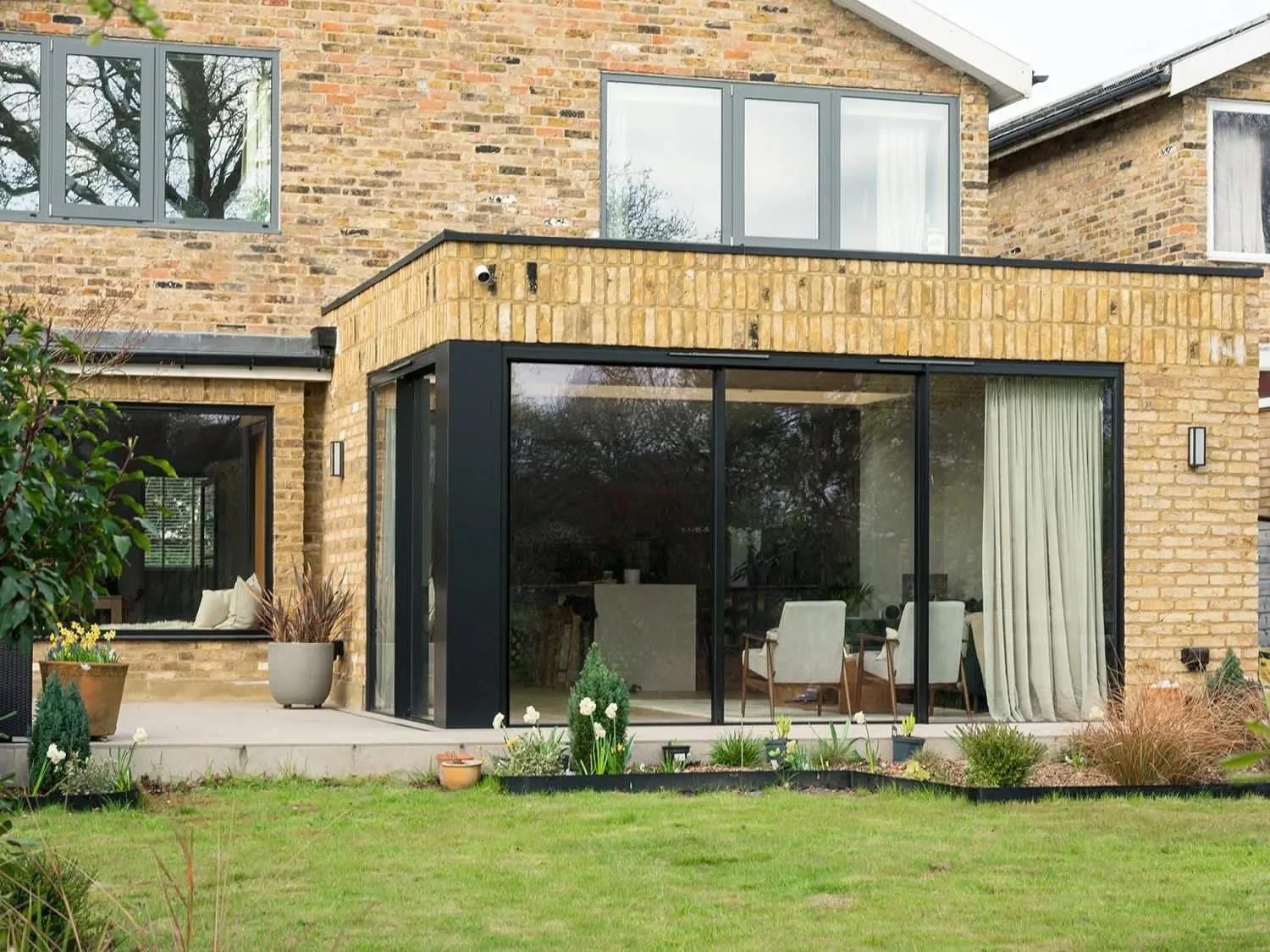 NOOR rear home extension — dark-framed sliding doors opening onto a landscaped garden